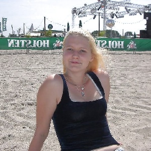 junge Blondine sitzt am Strand